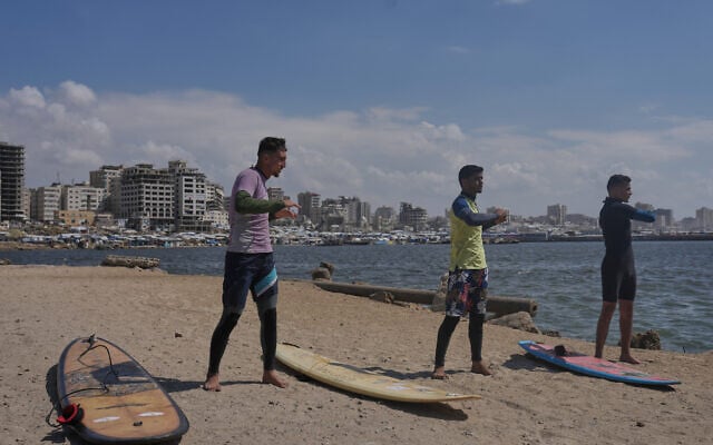 Palestinians Tahseen Abu Assi, left, Khalil Abu Jayyab, center, and Abed Rahim Alostaz warm up before surfing on the beach in Gaza City, Monday, May 4, 2026. (AP Photo/Jehad Alshrafi)