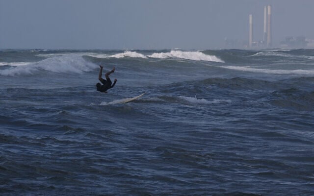 A Palestinian jumps into the waters of the Mediterranean Sea as he surfs on the beach in Gaza City, Monday, May 4, 2026. (AP Photo/Jehad Alshrafi)