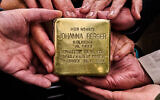 Relatives pose for a photograph holding a Holocaust plaque in German reading "Johanna Berger, born in 1893, lived here; deported on Nov. 17, 1941, murdered on Nov. 25, 1941 in Kowno/Kaunas Fort IX," prior to the placing of the so called "Stolperstein," in front of her former home in Berlin, Germany, May 6, 2026. (AP Photo/Markus Schreiber)