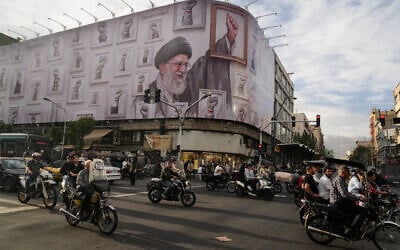 Motorbikes drive past a billboard with graphic showing the late Iranian Supreme Leader Ayatollah Ali Khamenei, in downtown Tehran, Iran, May 6, 2026. (AP Photo/Vahid Salemi)