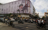 Motorbikes drive past a billboard with graphic showing the late Iranian Supreme Leader Ayatollah Ali Khamenei, who was killed in the U.S. and Israel strikes on Feb. 28, with his framed fist amongst his supporters framed fists in downtown Tehran, Iran, Wednesday, May 6, 2026. (AP Photo/Vahid Salemi)