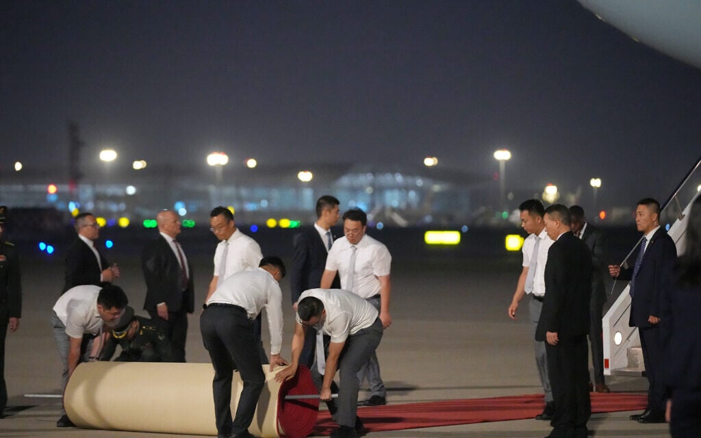 Workers roll out a red carpet as US President Donald Trump arrives on Air Force One, May 13, 2026, at Beijing Capital International Airport in Beijing (AP Photo/Mark Schiefelbein)