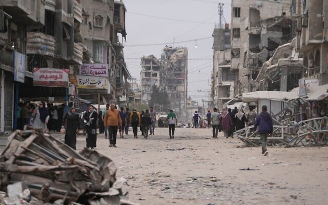 Palestinians walk along a street surrounded by buildings destroyed during the Israel-Hamas war, in Gaza City, Friday, May 15, 2026. (AP Photo/Abdel Kareem Hana)