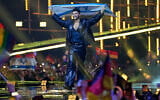 Noam Bettan from Israel walks onto the stage carrying his country's flag ahead of the Grand Final of the 70th Eurovision Song Contest in Vienna, Austria, May 16, 2026. (AP/Martin Meissner)