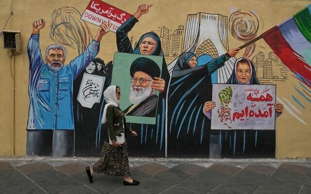 Illustrative: A woman walks past a pro-government mural in downtown Tehran, Iran, May 17, 2026. (AP Photo/Vahid Salemi)
