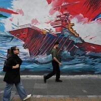 People walk past a mural depicting a US aircraft carrier under missile attack in downtown Tehran, Iran, May 17, 2026. (AP Photo/Vahid Salemi)