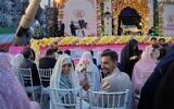 A bride and groom hold a rose as they pose for pictures during a mass wedding ceremony for participants in the "Janfada" ("Sacrifice for Iran") pro-government campaign in Tehran, Iran, May 18, 2026. (AP Photo/Vahid Salemi)