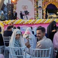 A bride and groom hold a rose as they pose for pictures during a mass wedding ceremony for participants in the "Janfada" ("Sacrifice for Iran") pro-government campaign in Tehran, Iran, May 18, 2026. (AP Photo/Vahid Salemi)