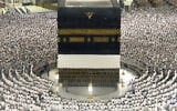 In this photograph taken through a glass fence, Muslim pilgrims are seen praying around the Kaaba, Islam's holiest site, at the Grand Mosque in Mecca, Saudi Arabia, during the annual Hajj pilgrimage, on May 22, 2026. (AP Photo/Altaf Qadri)