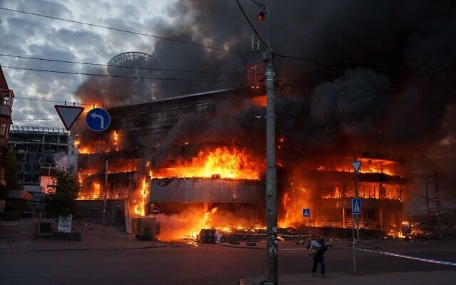 A man carries a box from a burning trade center after a Russian strike on Kyiv, Ukraine, on May 24, 2026. (AP Photo/Evgeniy Maloletka)