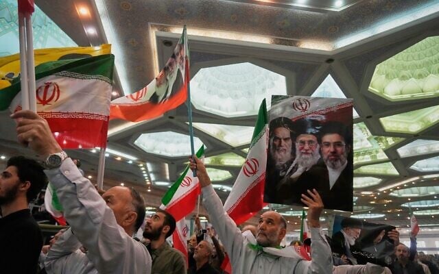 A man holds a sign depicting, from left, the late Iranian revolutionary founder Ayatollah Ruhollah Khomeini, the late supreme leader Ayatollah Ali Khamenei, and current Supreme Leader Ayatollah Mojtaba Khamenei during a ceremony honoring the armed forces and those killed in the war with Israel and the US at the Imam Khomeini Grand Mosque in Tehran, Iran, May 24, 2026. (AP Photo/Vahid Salemi)