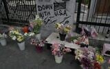 An anti-US graffiti is painted on a wall as flowers are displayed by a street vendor in downtown Tehran, Iran, May 24, 2026. (AP Photo/Vahid Salemi)