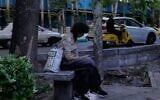 A woman checks her smartphone while sitting on a bench along a sidewalk in northern Tehran, Iran, Tuesday, May 26, 2026. (AP Photo/Vahid Salemi)