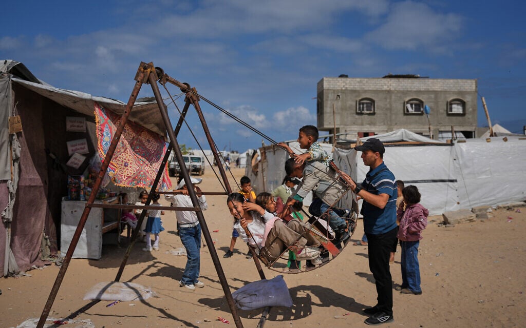 Displaced Palestinian children play on a swing at a tent camp during the Muslim holiday of Eid al-Adha in Khan Younis, southern Gaza Strip, May 27, 2026. (AP Photo/Abdel Kareem Hana)