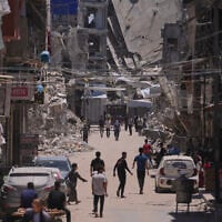 Palestinians walk along a street surrounded by buildings destroyed by Israeli military strikes during the Israel-Hamas war in Khan Younis, southern Gaza Strip, May 29, 2026. (AP Photo/Abdel Kareem Hana)