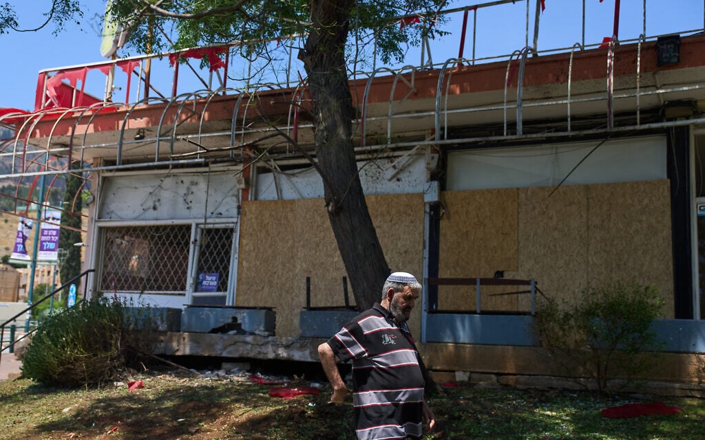 A local resident walks past the site struck by a rocket fired from Lebanon in Kiryat Shmona, northern Israel, May 31, 2026. (AP Photo/Ariel Schalit)