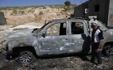 Palestinians inspect a burned vehicle following an attack by Israeli extremist settlers in the Wadi Rahim area of Hebron in the West Bank, May 1, 2026. (Wisam Hashlamoun/Flash90)