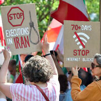 Demonstrators holding signs as they gather near the Francis Scott Key Bridge during a rally in support of the Iranian people and to condemn the execution of political prisoners in Iran, in Washington, DC, on May 16, 2026. (Amid Farahi/ AFP)