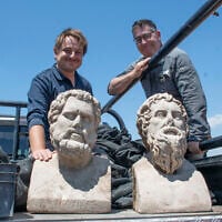 Archaeologists Eliran Oren and Michael Sorotskin with the statues discovered in Binyamina. (Yoli Schwartz/Israel Antiquities Authority)