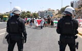 Police officers stand guard as pro-Palestinian demonstrators stage a demonstration against the arrival of Israeli cruise passengers in Heraklion Port, on the island of Crete, on August 28, 2025. (Photo by Costas METAXAKIS / AFP)