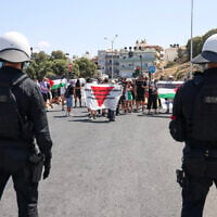 Police officers stand guard as pro-Palestinian demonstrators stage a demonstration against the arrival of Israeli cruise passengers in Heraklion Port, on the island of Crete, on August 28, 2025. (Photo by Costas METAXAKIS / AFP)