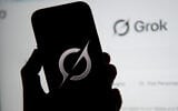 In this photo illustration, the Grok logo is seen on a mobile phone next to the website displayed on a computer screen in Bogota on February 12, 2026. (Pablo Vera/AFP)