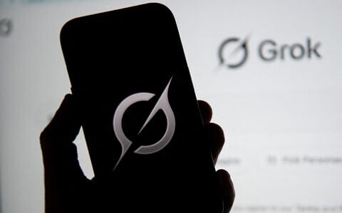 In this photo illustration, the Grok logo is seen on a mobile phone next to the website displayed on a computer screen in Bogota on February 12, 2026. (Pablo Vera/AFP)