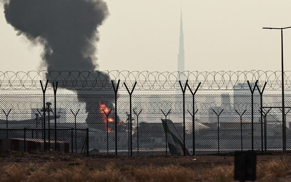 The Dubai skyline with the landmark Burj Khalifa skyscraper (R) is pictured as a smoke plume rises from an ongoing fire near Dubai International Airport on March 16, 2026. (AFP)