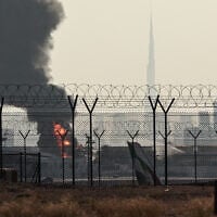 The Dubai skyline with the landmark Burj Khalifa skyscraper (R) is pictured as a smoke plume rises from an ongoing fire near Dubai International Airport on March 16, 2026. (AFP)