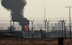 The Dubai skyline with the landmark Burj Khalifa skyscraper (R) is pictured as a smoke plume rises from an ongoing fire near Dubai International Airport on March 16, 2026. (AFP)