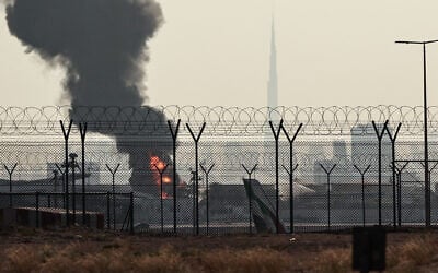 The Dubai skyline with the landmark Burj Khalifa skyscraper (R) is pictured as a smoke plume rises from an ongoing fire near Dubai International Airport on March 16, 2026. (AFP)