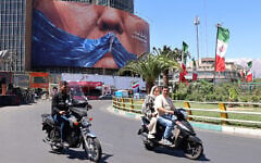 Commuters drive past an anti-US billboard referring to President Donald Trump and the Strait of Hormuz, installed on a building at the Valiasr Square in Tehran, on May 10, 2026. (Photo by ATTA KENARE / AFP)
