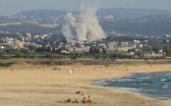 A photograph taken from the southern city of Tyre shows people sunbathing on the beach, as smoke rises from the site of an Israeli airstrike on Hezbollah in the village of Deir Qanoun Ras al-Ain on June 8, 2026. (Kawnat Haju/AFP)