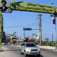 A car loaded with suitcases leaves Tyre through a Hezbollah placard in southern Lebanon on June 9, 2026 (KAWNAT HAJU / AFP) /