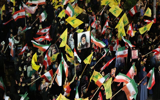 Supporters of Iran-backed terror group Hezbollah wave flags and hold a portrait of slain leader Hassan Nasrallah during an anti-US and anti-Israel protest in Beirut's southern suburbs on June 10, 2026. (Anwar AMRO / AFP)