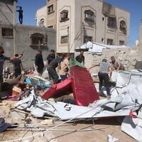 Displaced Palestinians remove sand and debris from their tent homes following an Israeli military strike in Khan Younis, southern Gaza Strip, on June 14, 2026. (Bashar Taleb/AFP)