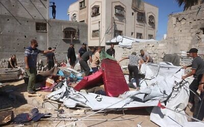 Displaced Palestinians remove sand and debris from their tent homes following an Israeli military strike in Khan Younis, southern Gaza Strip, on June 14, 2026. (Bashar Taleb/AFP)