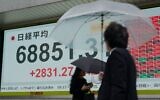 Pedestrians walk past an electronic quotation board displaying the Nikkei Stock Average on the Tokyo Stock Exchange in Tokyo on June 15, 2026. (Kazuhiro NOGI / AFP)