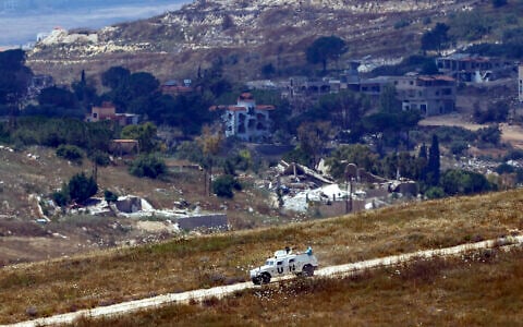 This picture taken from a position in northern Israel, near the border with Lebanon shows a United Nations Interim Force in Lebanon (UNIFIL) armored vehicle driving past destroyed buildings in southern Lebanon on June 22, 2026. (Jalaa MAREY / AFP) /