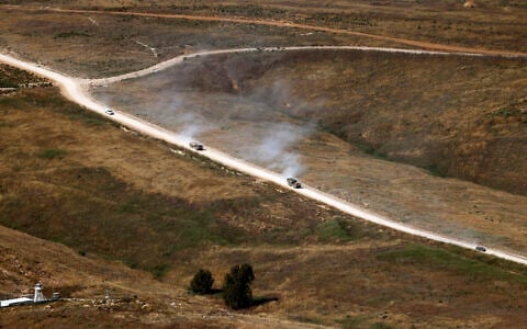 This picture taken from a position in the Upper Galilee region in northern Israel, shows Israeli military vehicles driving along a road in southern Lebanon on June 22, 2026 (Jalaa MAREY / AFP) /
