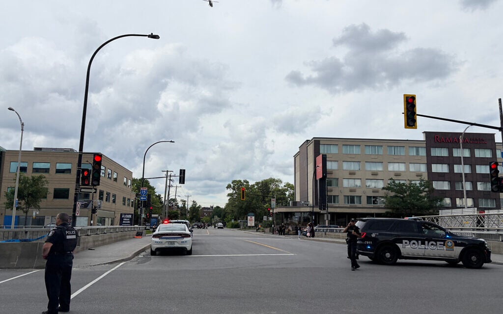 Police and a police vehicle are seen near the scene of a shooting in Montreal on June 22, 2026, which left two people dead, in addition to the attacker. (Daphné Lemelin/AFP)