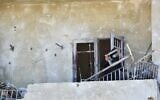 A Lebanese woman removes broken metal railing from her damaged house following Israeli military strikes, in the southern Lebanese village of Srifa on June 24, 2026. (Photo by Fadel ITANI / AFP) /