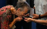 A relative of Dimitris Vafeiadis kisses his personal belongings during a ceremony for the return of personal belongings of Greek prisoners from Nazi forced labor camps to their families, held as part of the international StolenMemory campaign, at the Greek foreign ministry in Athens on June 25, 2026. (Angelos Tzortzinis/AFP)