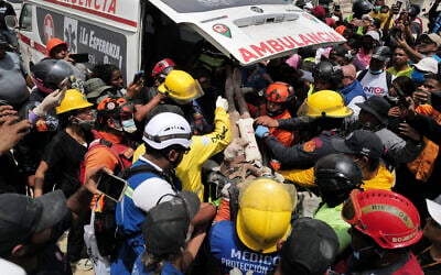 Rescuers load a person onto an ambulance after being pulled alive from the rubble of a collapsed building in Caraballeda, La Guaira state, Venezuela, on June 28, 2026, following back-to-back earthquakes. (Mauricio Valenzuela/AFP)