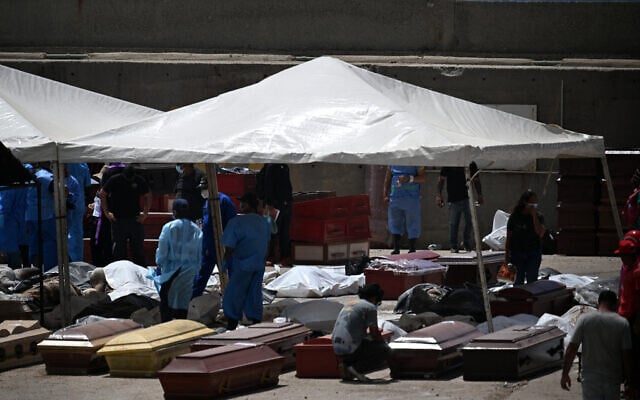 Forensic experts stand amid victims and coffins in La Guaira, La Guaira State, Venezuela on June 29, 2026, following the June 24 twin earthquakes. (Juan BARRETO / AFP)