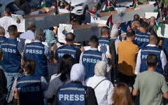 Palestinian journalists carry mock coffins of Palestinian journalists who they say were killed in the war in Gaza during a symbolic funeral procession toward a United Nations office, in the West Bank city of Ramallah, Tuesday, November 7, 2023. (AP/Nasser Nasser)