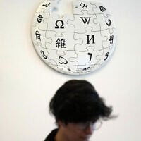 A volunteer Wikipedia editor sits below a Wikipedia logo displayed at the Wikimedia Foundation office in San Francisco, California, January 12, 2026. (AP Photo/Jeff Chiu)
