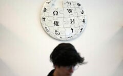 A volunteer Wikipedia editor sits below a Wikipedia logo displayed at the Wikimedia Foundation office in San Francisco, California, January 12, 2026. (AP Photo/Jeff Chiu)