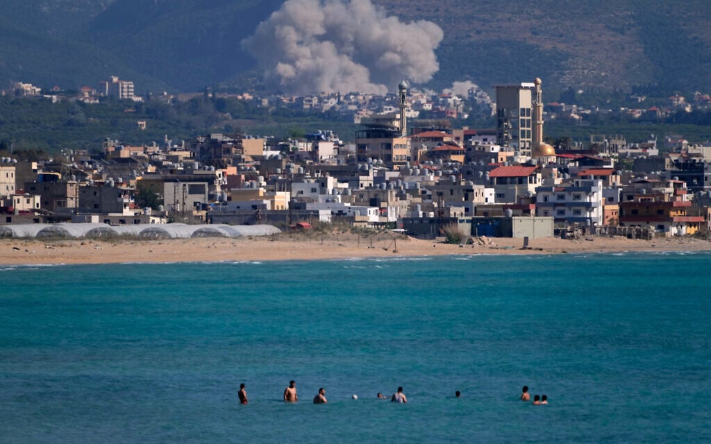 People swim on a public beach as smoke rises from an Israeli airstrike that hit a village near the southern port city of Tyre, Lebanon, June 2, 2026. (AP Photo/Mohammed Zaatari)