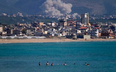 People swim on a public beach as smoke rises from an Israeli airstrike that hit a village near the southern port city of Tyre, Lebanon, June 2, 2026. (AP Photo/Mohammed Zaatari)